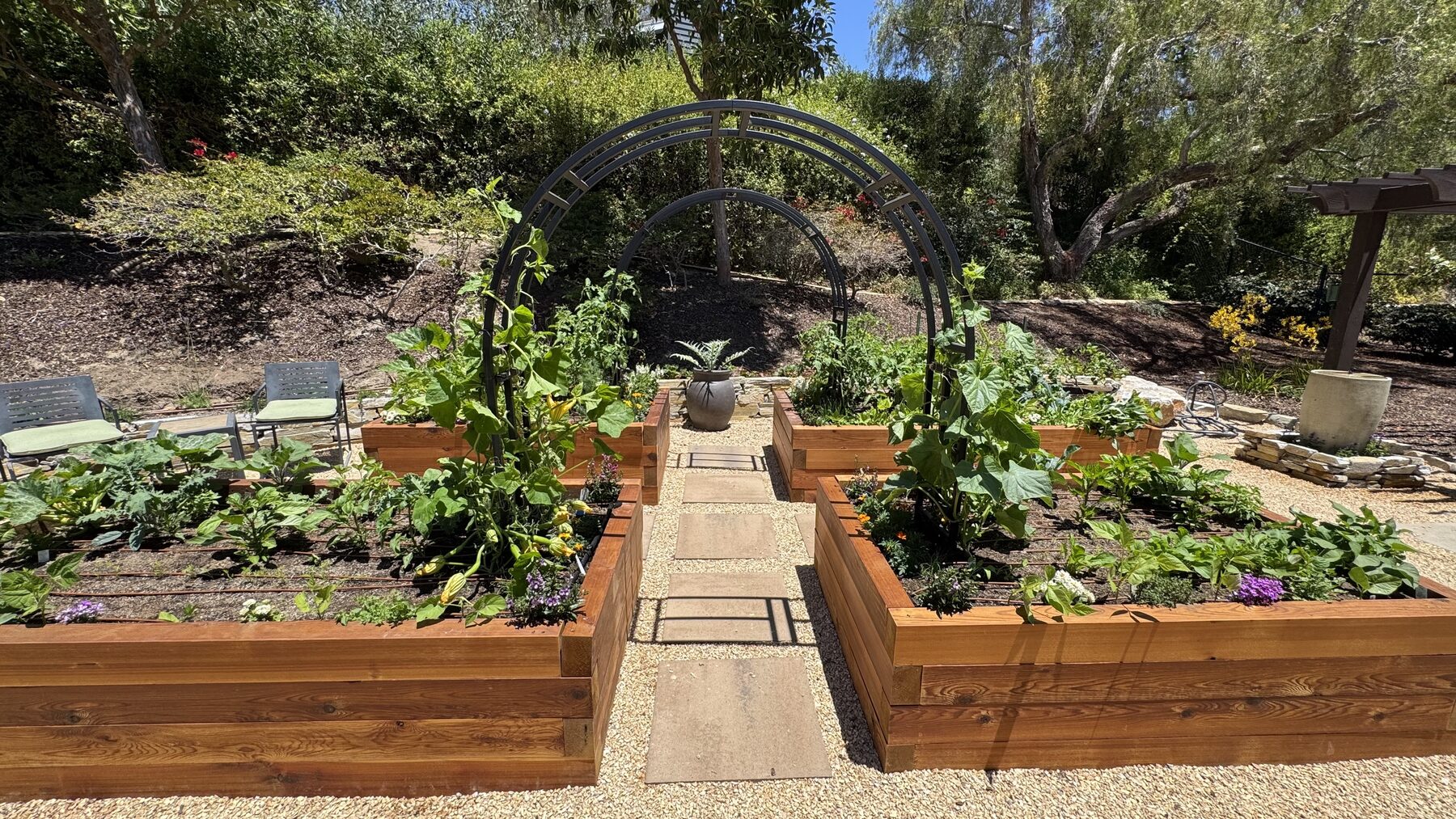 The Tracy Garden Package: a symmetrical path with twin black arch trellises leading to a stone urn